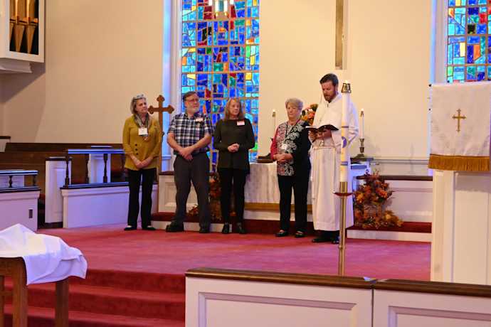 Scott Taylor reading text with member of congregation on stage