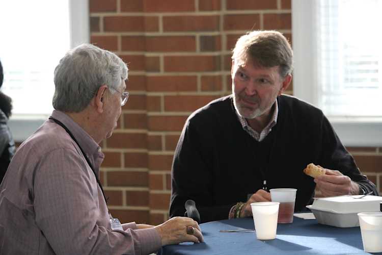 Two members of IPUMC talking at table with food and drinks