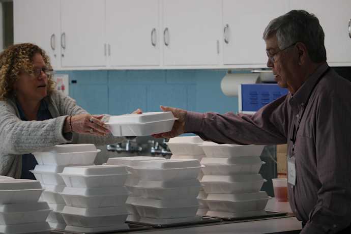 Two helpers at IPUMC with food to-go boxes