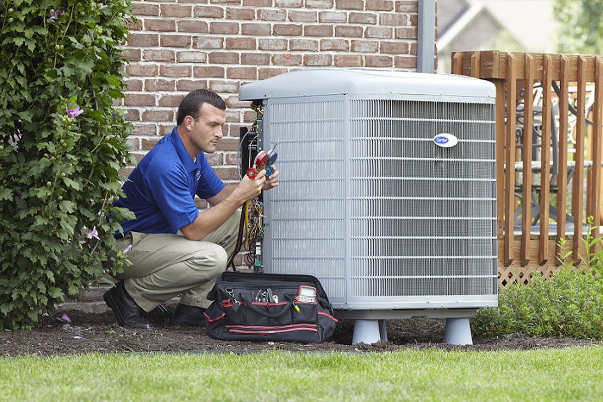 Technician performing HVAC maintenance on a central air conditioner