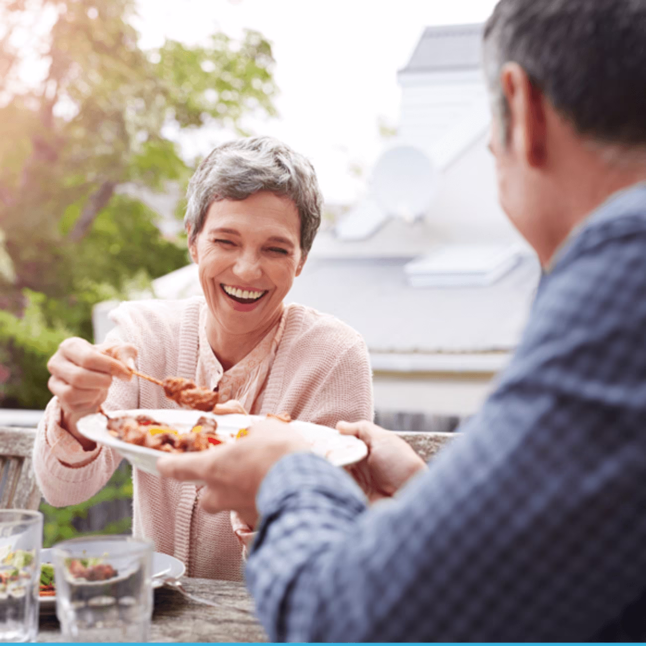 A smiling woman is being served a plate of food by a man.