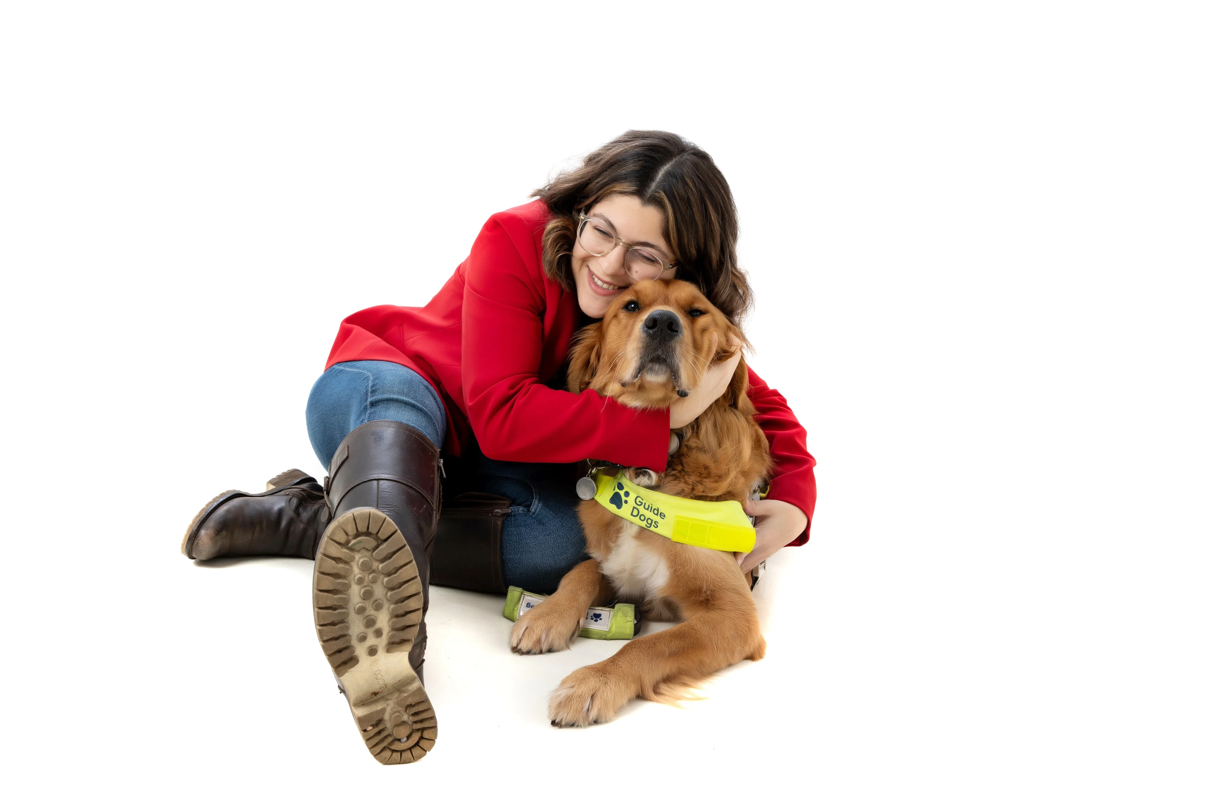 Zein and guide dog Mitch sit on the floor together and Zein has her arms around Mitch.