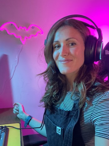 Photo of Lucy Voakes wearing headphones while gaming at a desk.