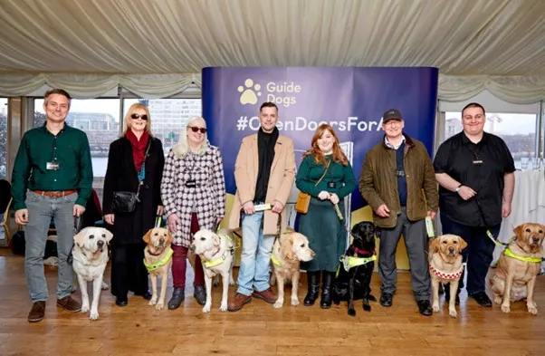 Seven guide dog owners and their guide dogs photographed at the Open Doors Westminster event