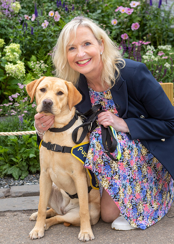 Carol Kirkwood smiling with puppy Flash