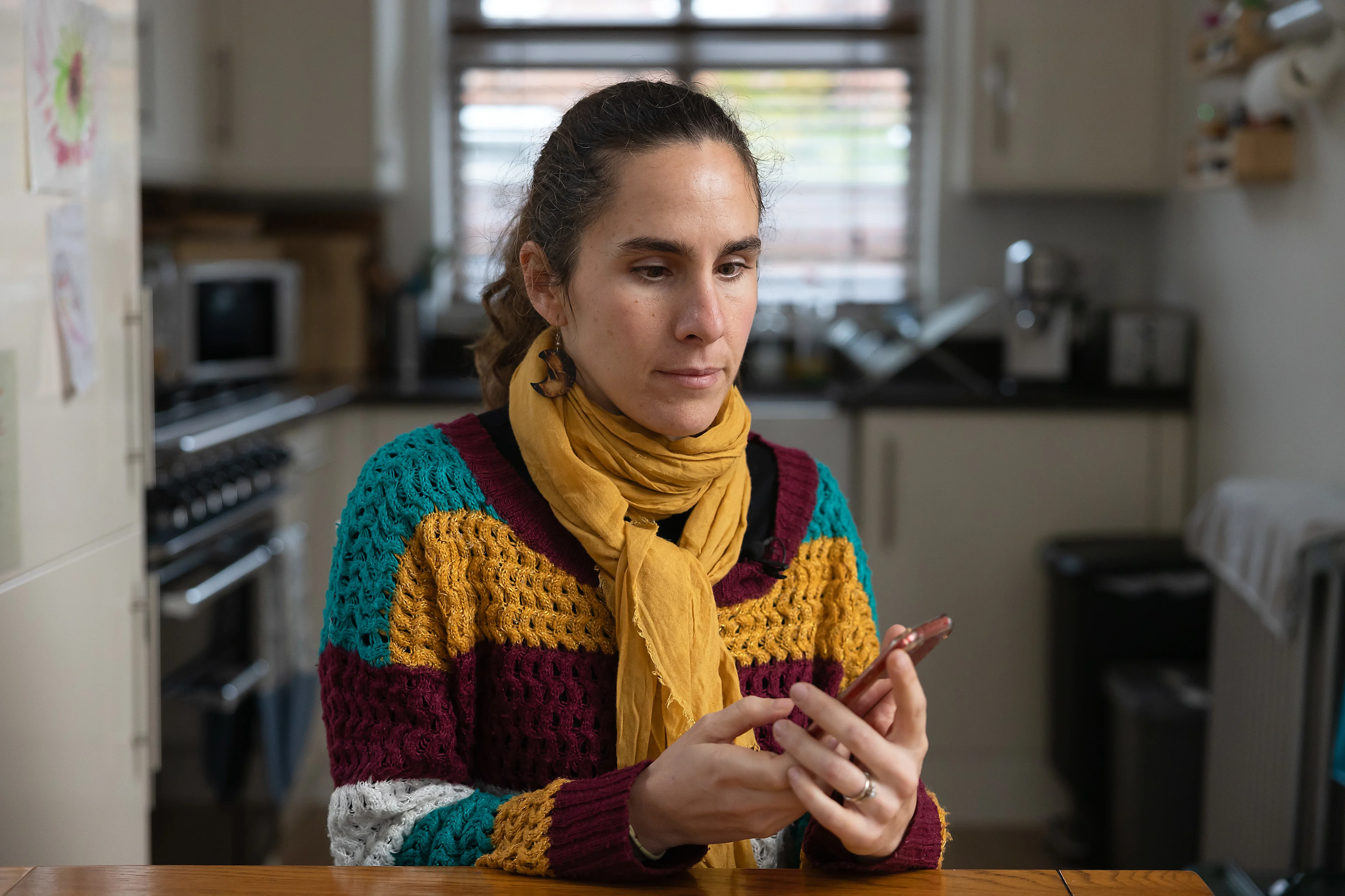 Alba uses her iPhone at her kitchen table