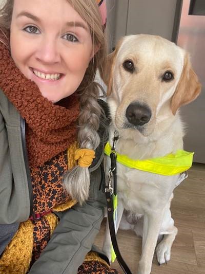 Lynette pictured looking at the camera with her guide dog Dubs