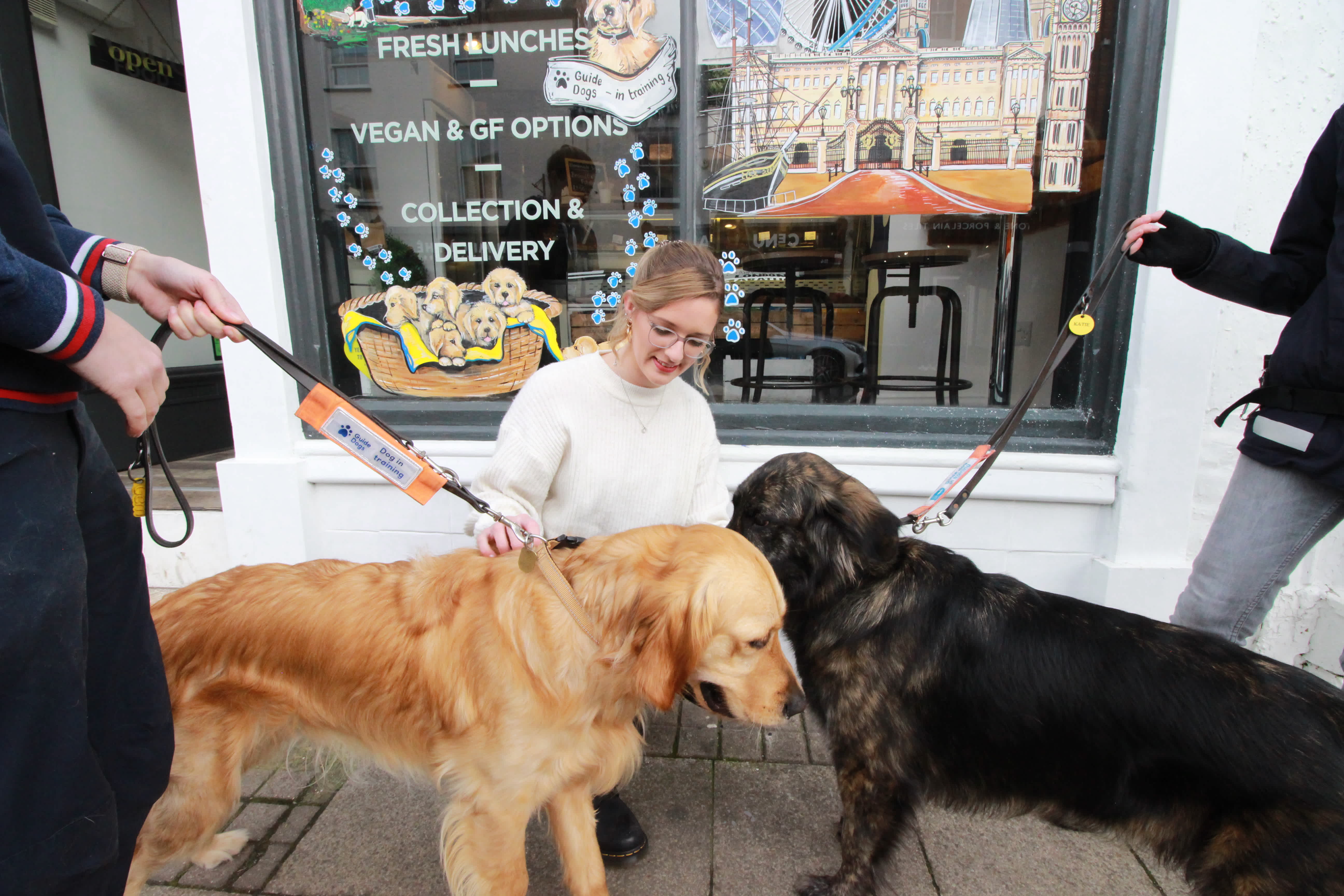 Photo shows Alice from Rustic food kneeling next to Ashleigh, a Golden Retriever cross German Shepherd and Charlie, a Golden Retriever, outside Rustic Food.
