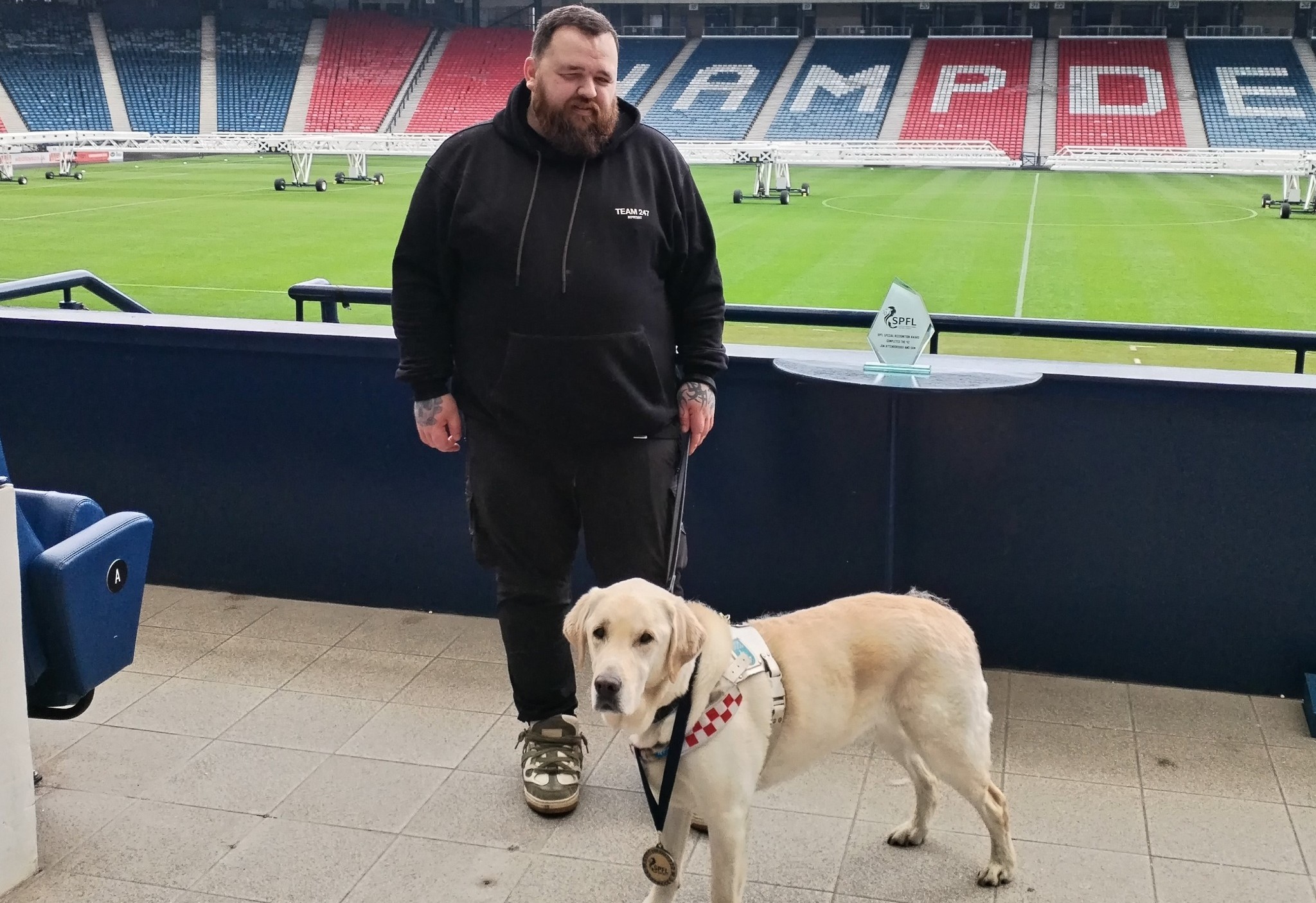 Jon and Sam stood inside Hampden Park stadium with the pitch behind them