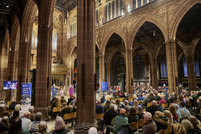 A view of the audience in Manchester Cathedral, which is crowded with attendees sitting watching the concert.