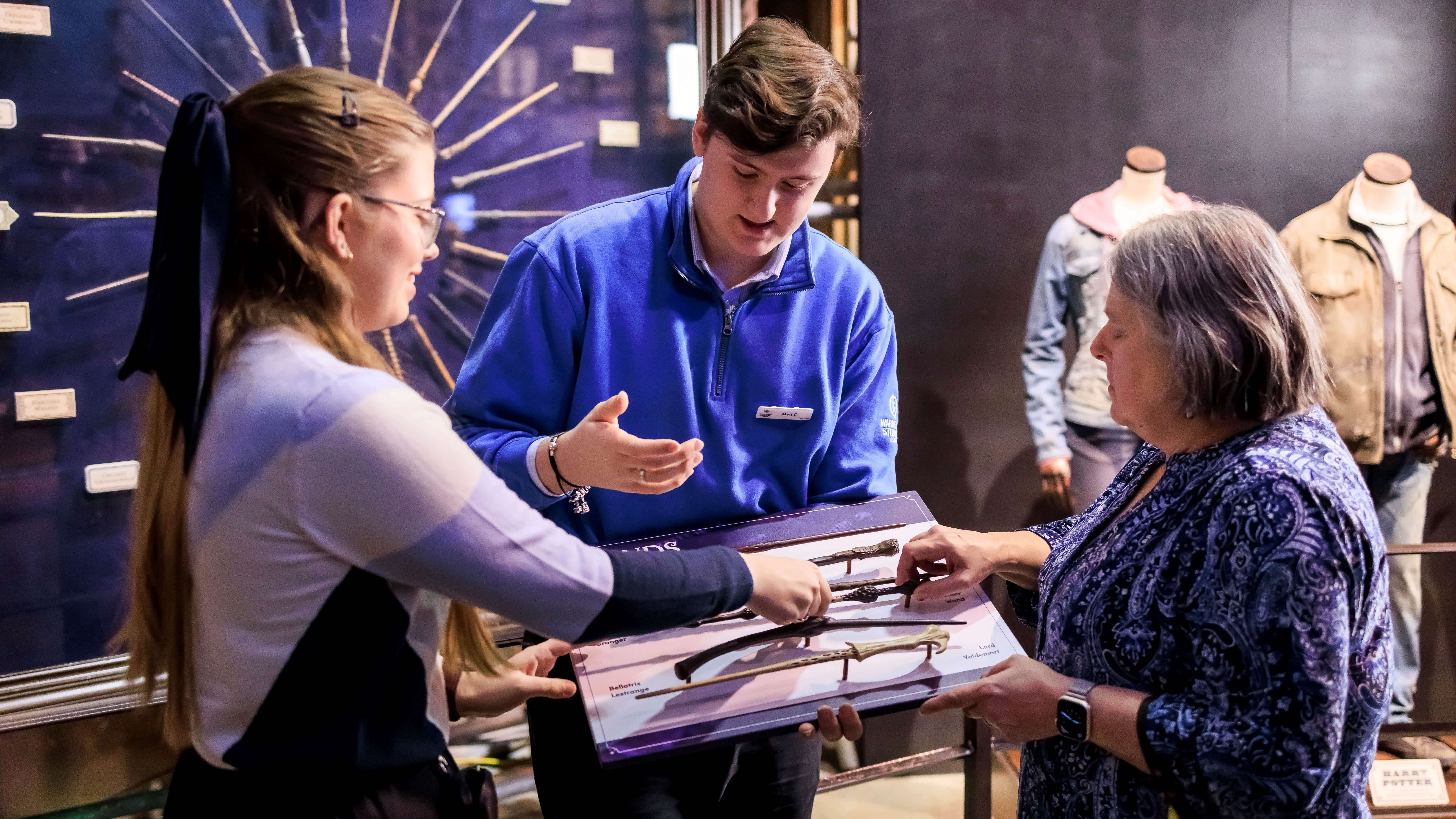 Two people with sight loss touch wand props on a Tactile Tour at the Warner Bros Studio Tour