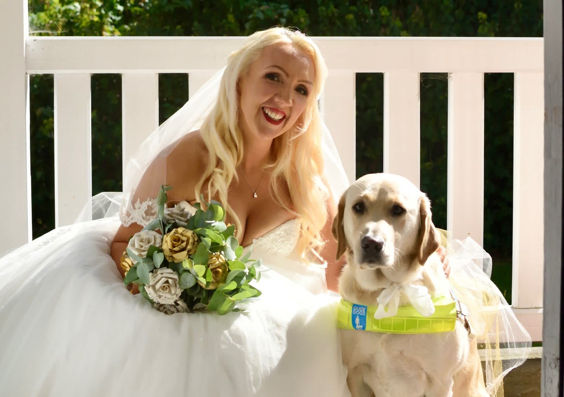 Lizzie wears her wedding dress and holds her bouquet on her wedding day next to her guide dog Ziggy