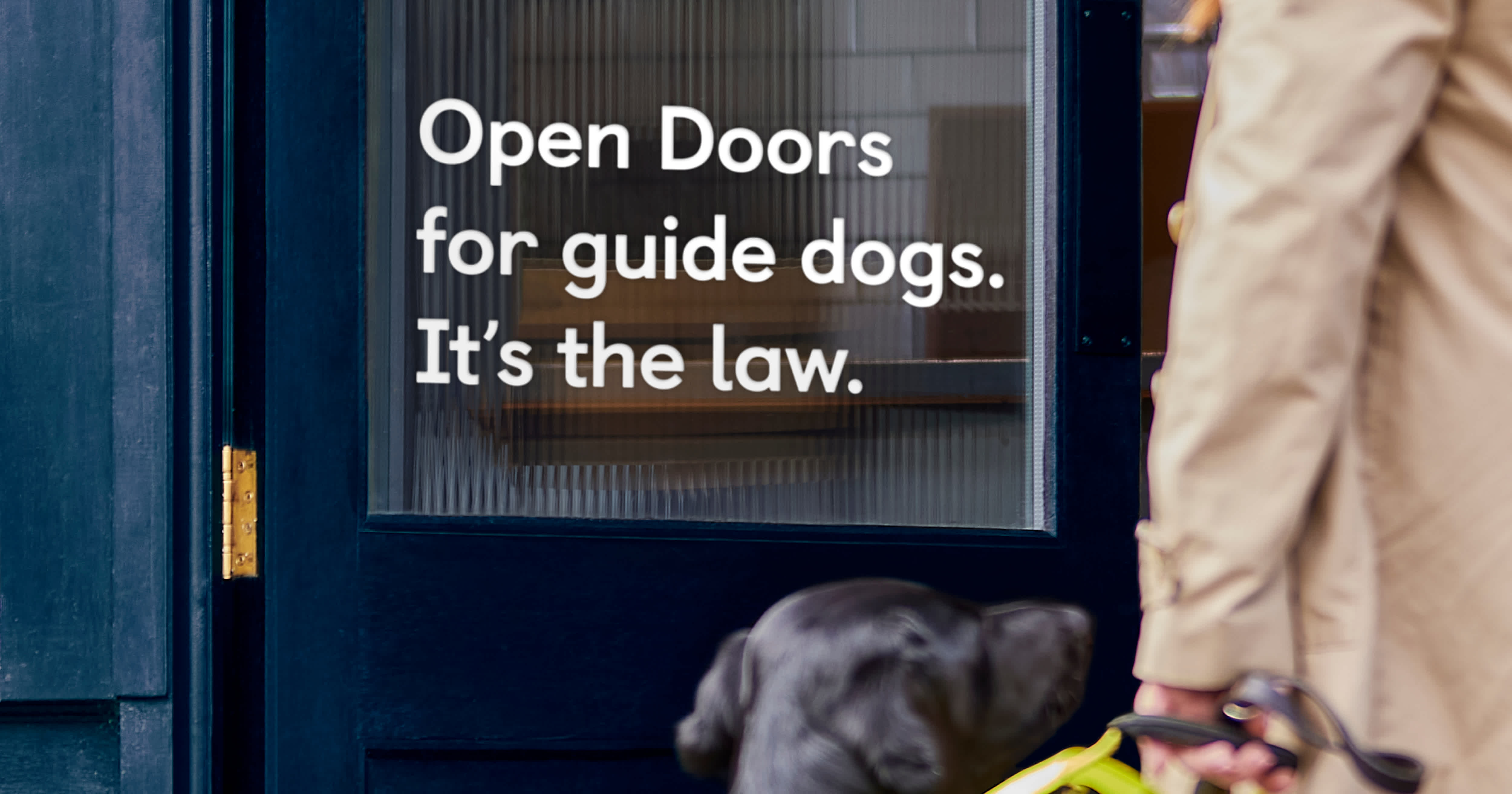 Guide dog owner and guide dog walk towards an open door of a food business.
