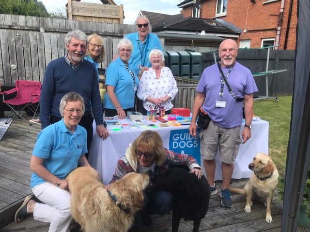 Volunteer fundraising group coordinator, Ian Carnachan, surrounded by his fundraising group and three guide dogs in training