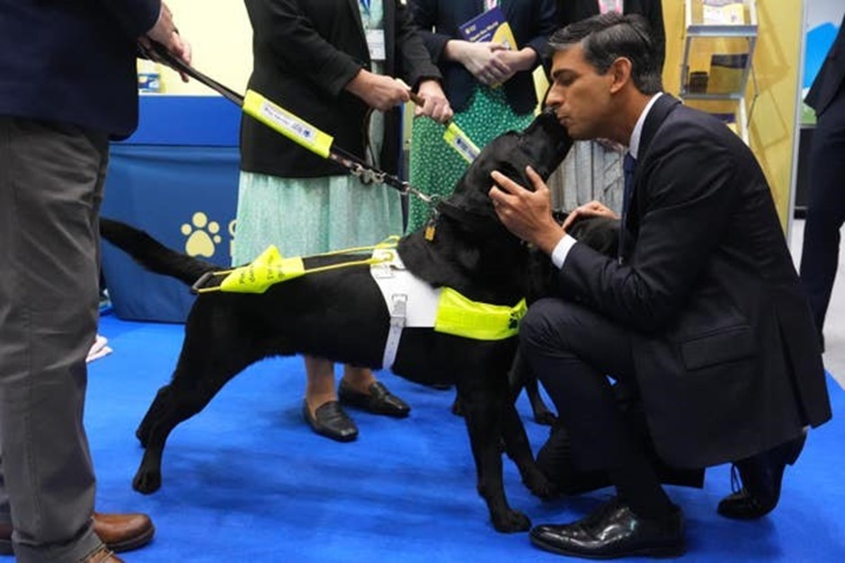 Prime Minister Rishi Sunak kneels down to interact with guide dog Stevie at the Guide Dogs stand at the 2023 Conservative Party Conference in Manchester. 