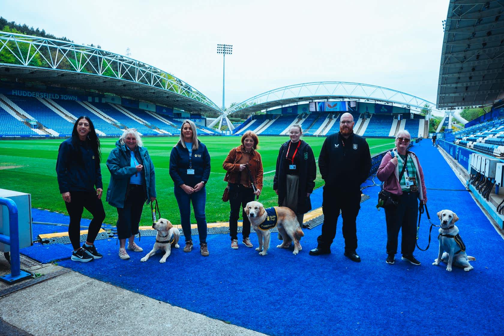 Guide Dogs staff members, volunteers and Huddersfield Town staff with guide dog puppies inside the Accu Stadium