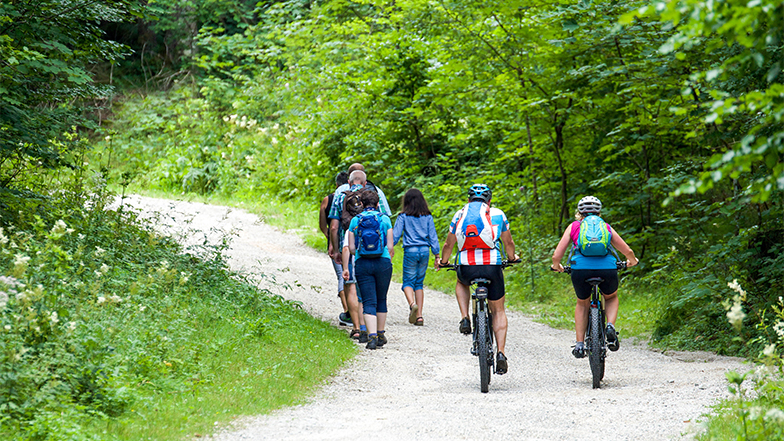 Two people riding bicycles past a group of walkers in the countryside