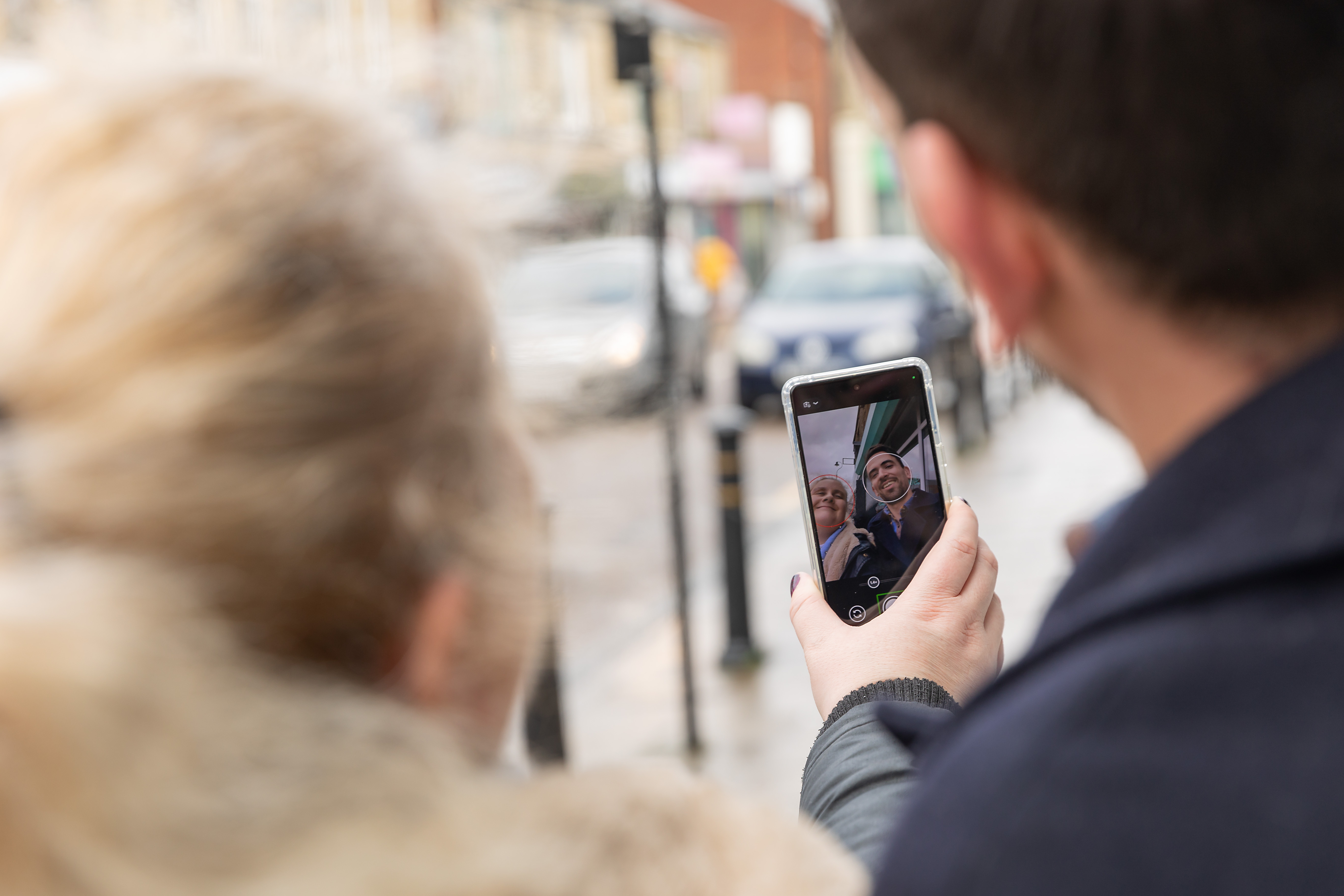 Two people taking a selfie on the Google Pixel using the Guided Frame feature, they smile into the phone's front camera.