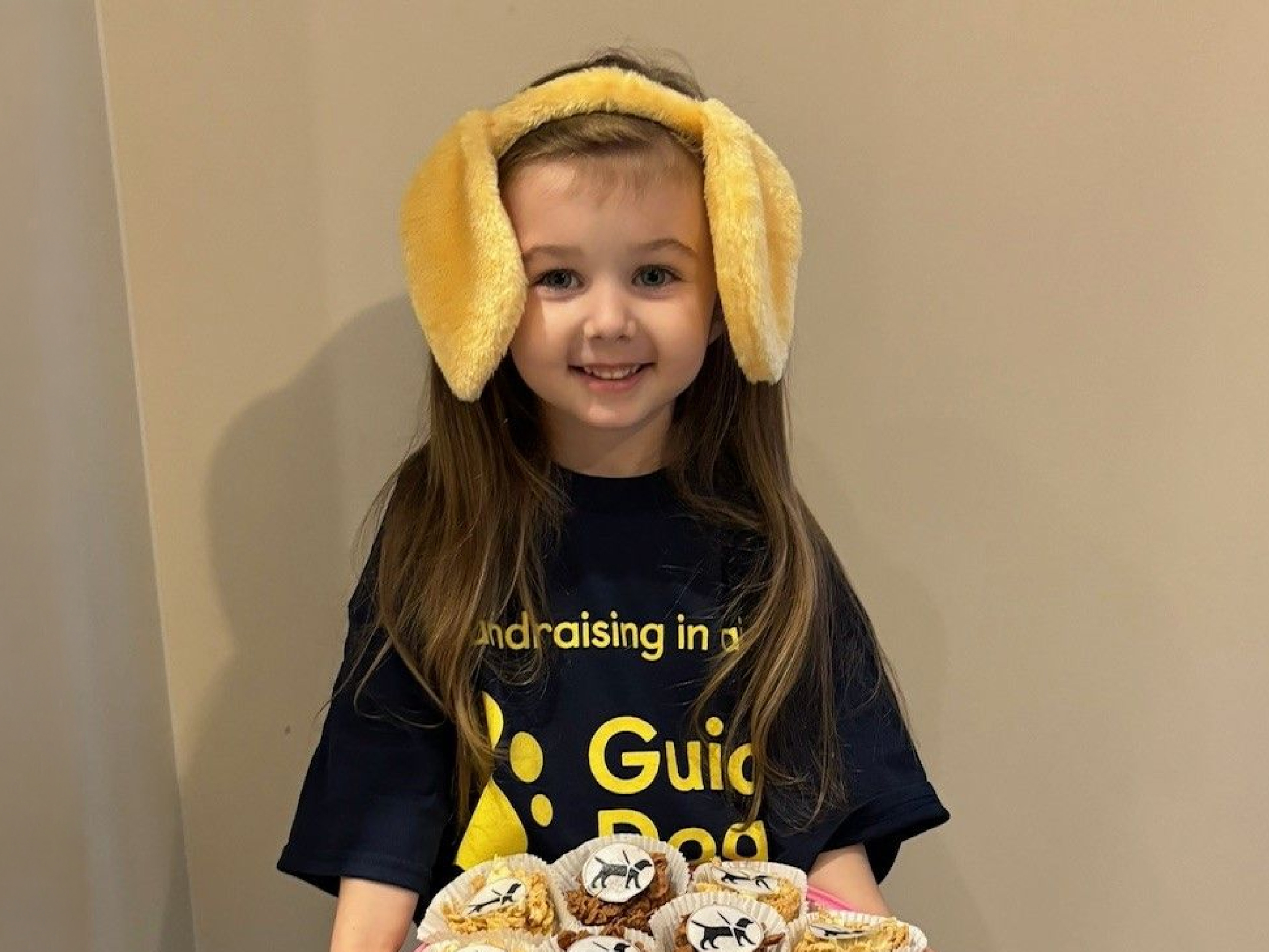 A young fundraiser called Madison holding a plate of homemade cakes.