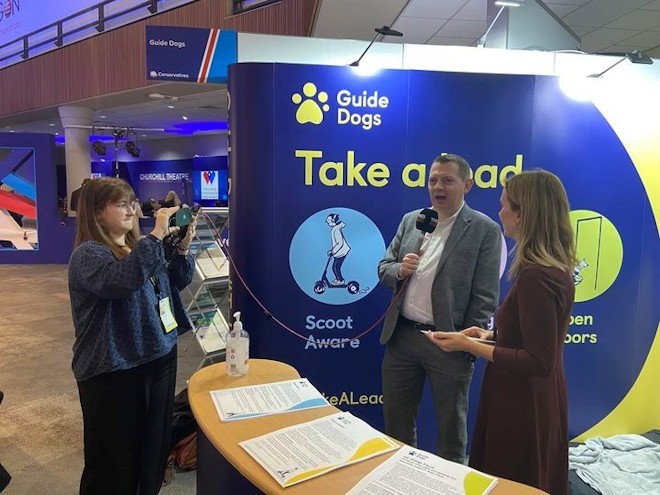 Guide Dogs staff interviewed by Times Radio journalist on the Guide Dogs stand at the Conservative Party Conference stand. 