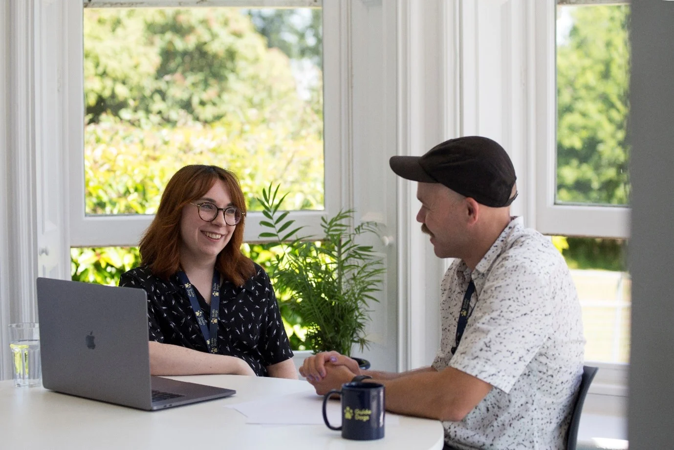 Two people sat chatting at a desk.