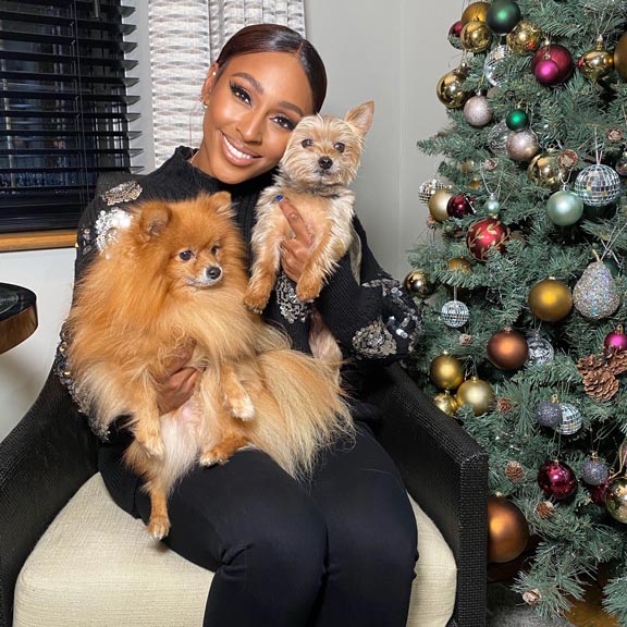 Alexandra Burke smiles with her two dogs next to the Christmas tree