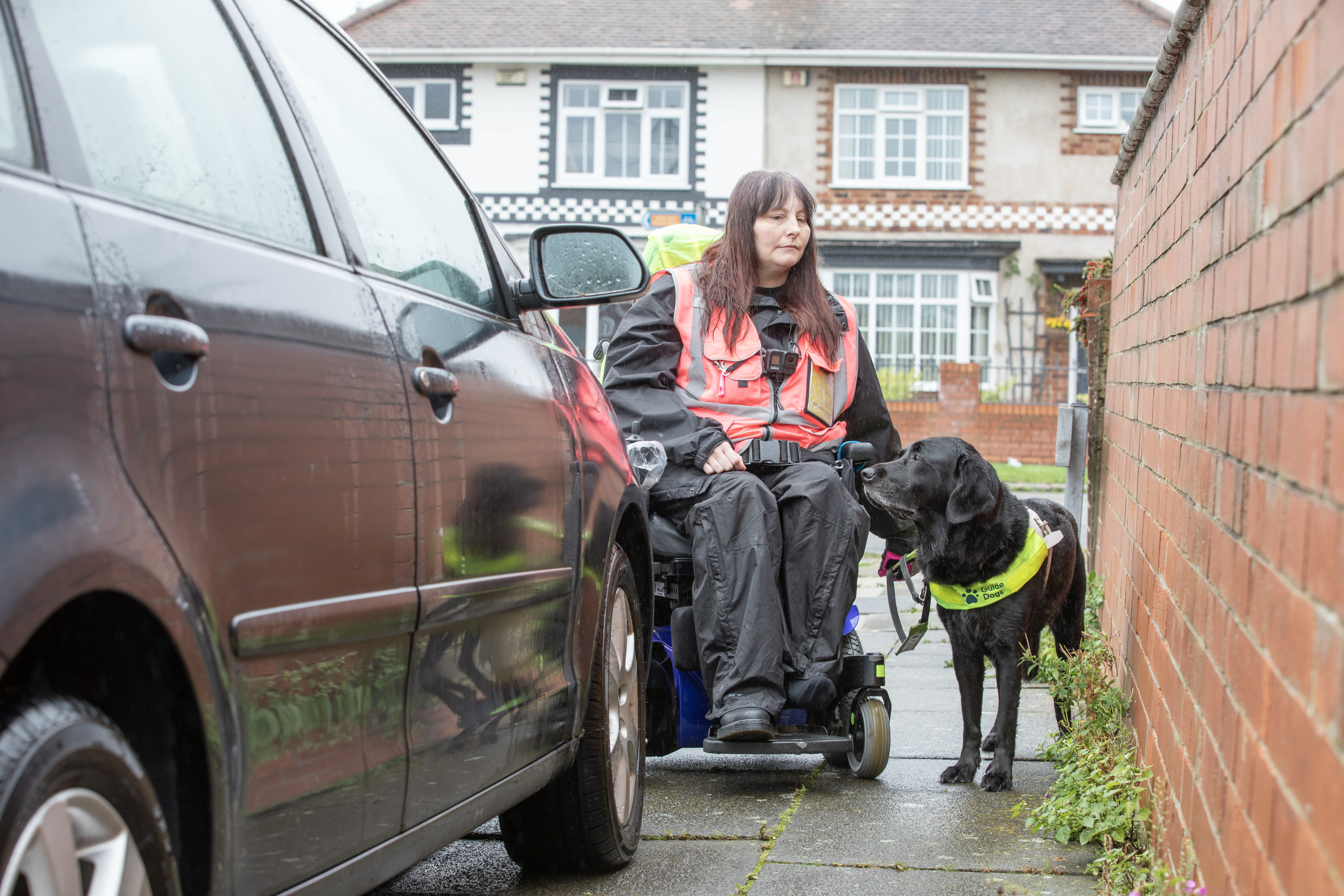 Guide dog owner Julie Pilsworth and guide dog Maeve stuck behind a car parked on the pavement and unable to pass. 