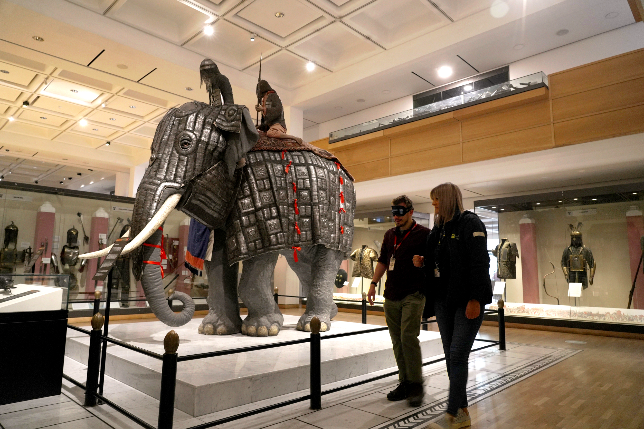 Guide Dogs staff member Kelle guides a Royal Armouries staff member around an armoured elephant exhibit at the museum