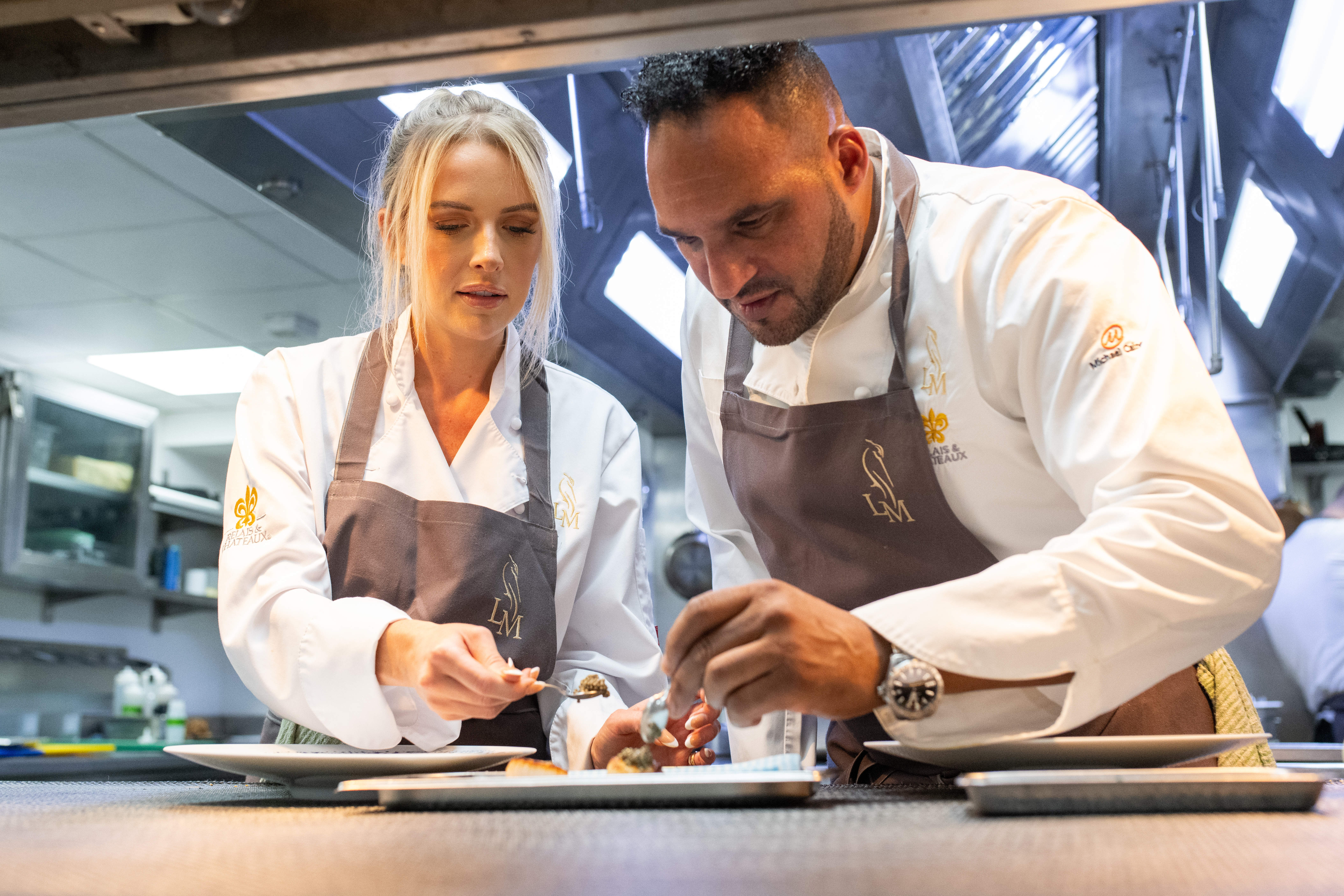 Faye Winter and chef Michael Caines add the finishing touches to a plate of food. 