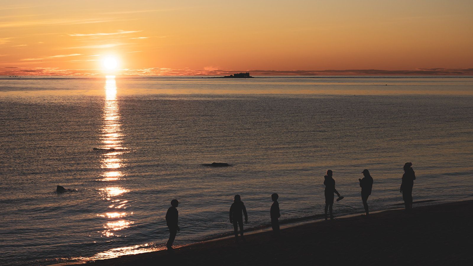 Lapsia ja nuoria rannassa auringonlaskua katselemassa Kalajoella