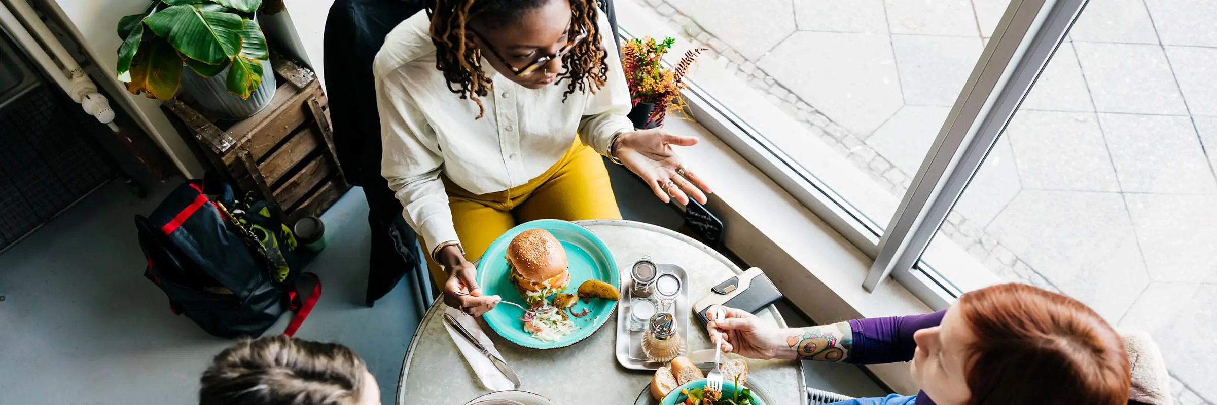 Three women are having lunch at a restaurant together and talking.