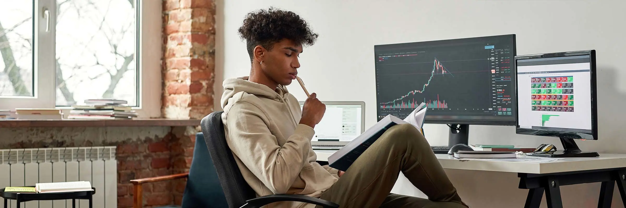 Young investor reads about investing while following a stock graph on the computer