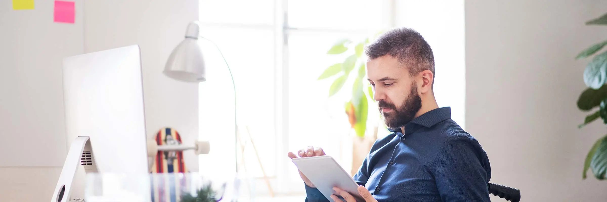 Businessman in wheelchair with tablet in his office