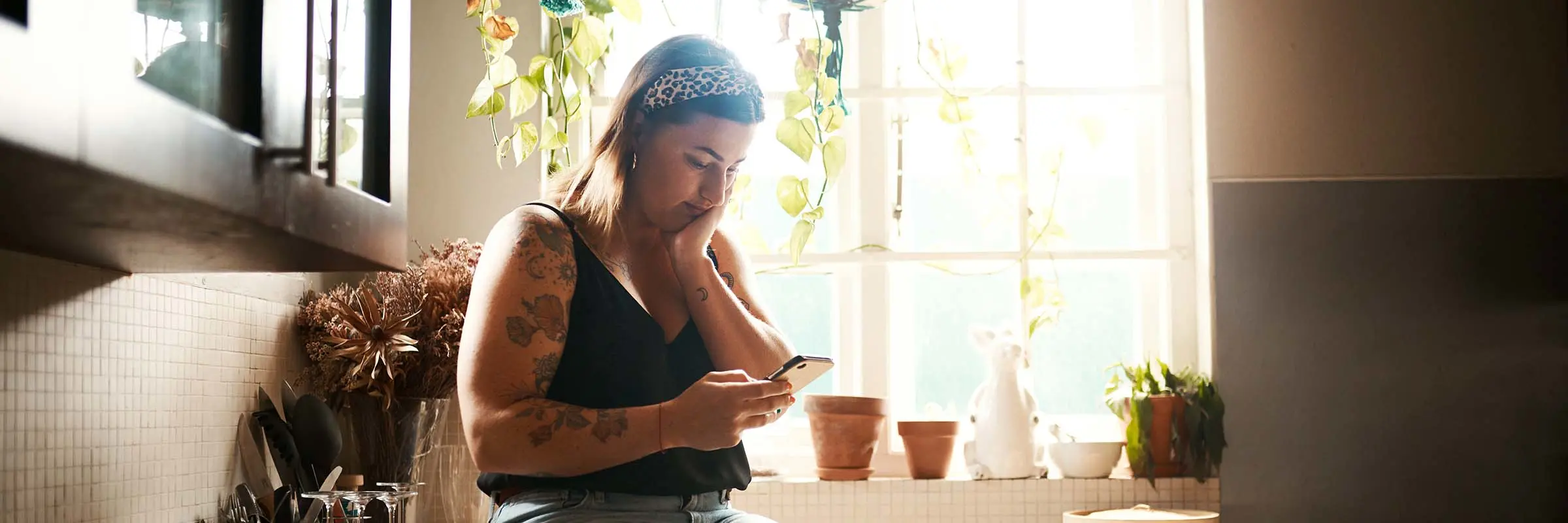 Woman sitting on counter looking at her phone