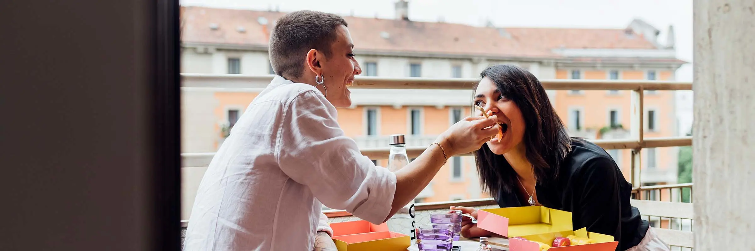 Image of a couple feeding each other sushi on a balcony