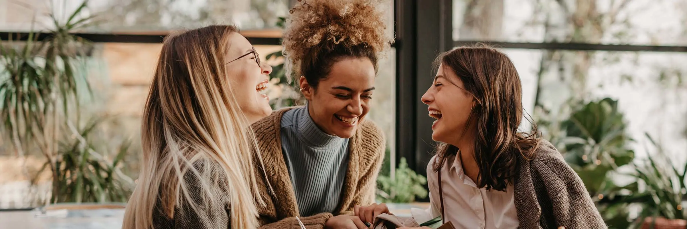 Three friends having their coffee togther while smiling. 