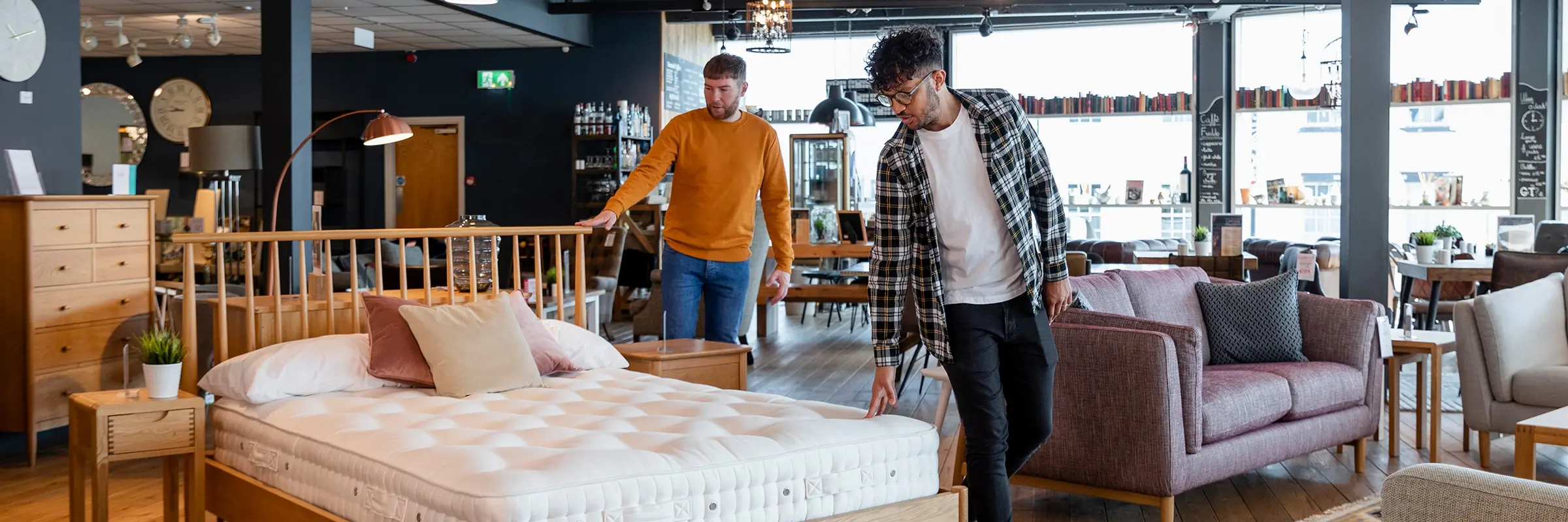 Two men examine a bed for sale inside a furniture store.