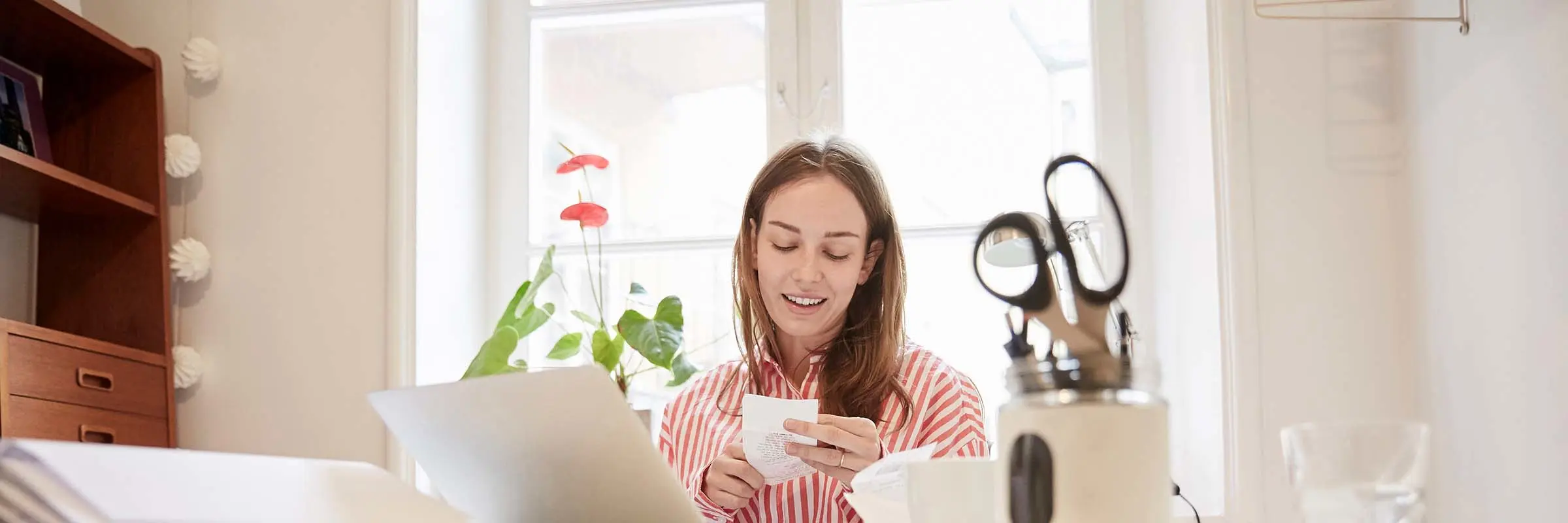 Woman looking at a receipt while sitting at a desk