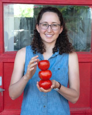 woman holding apples in front of a red door 