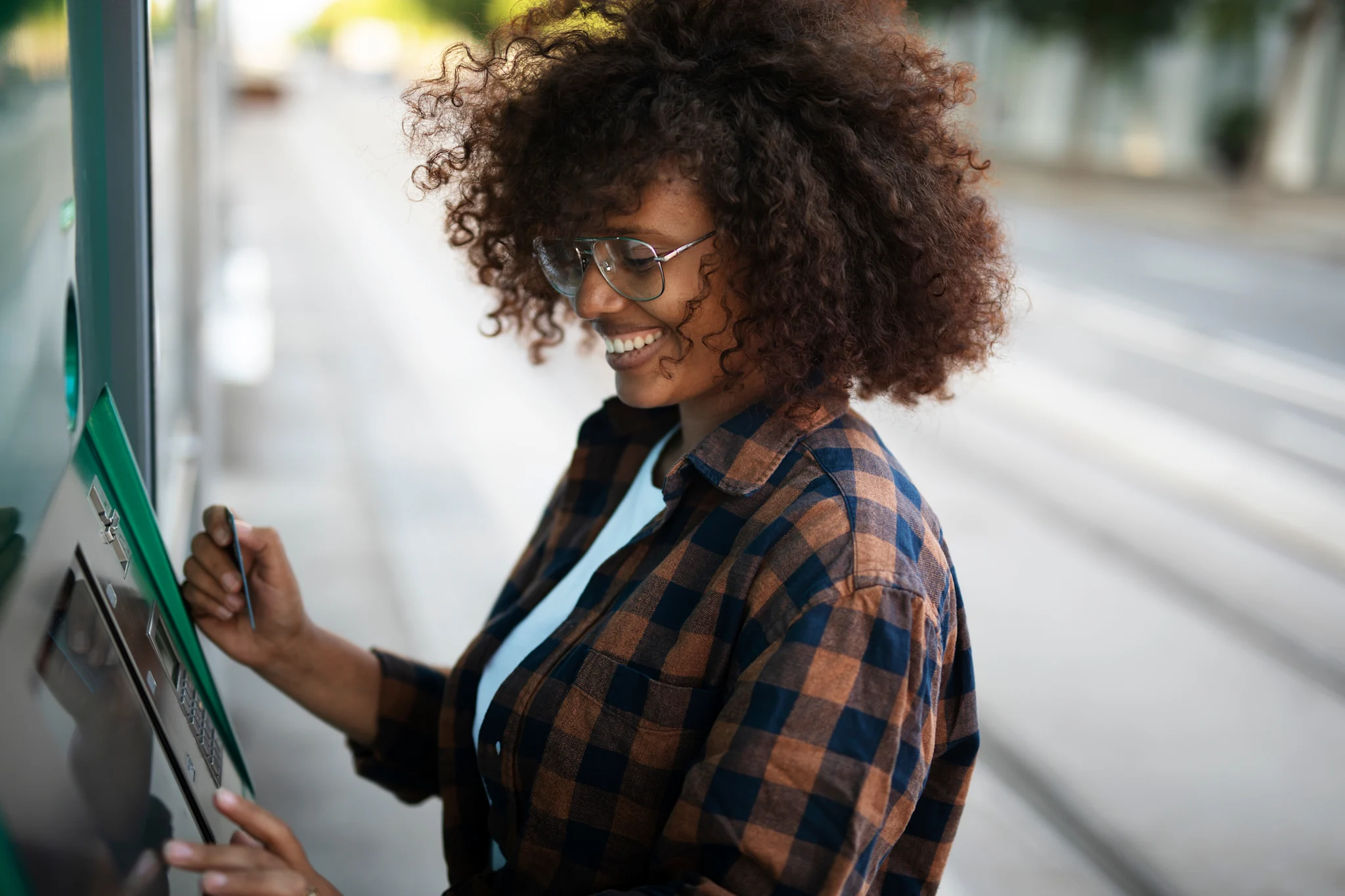 woman smiling and getting cash at an atm outside