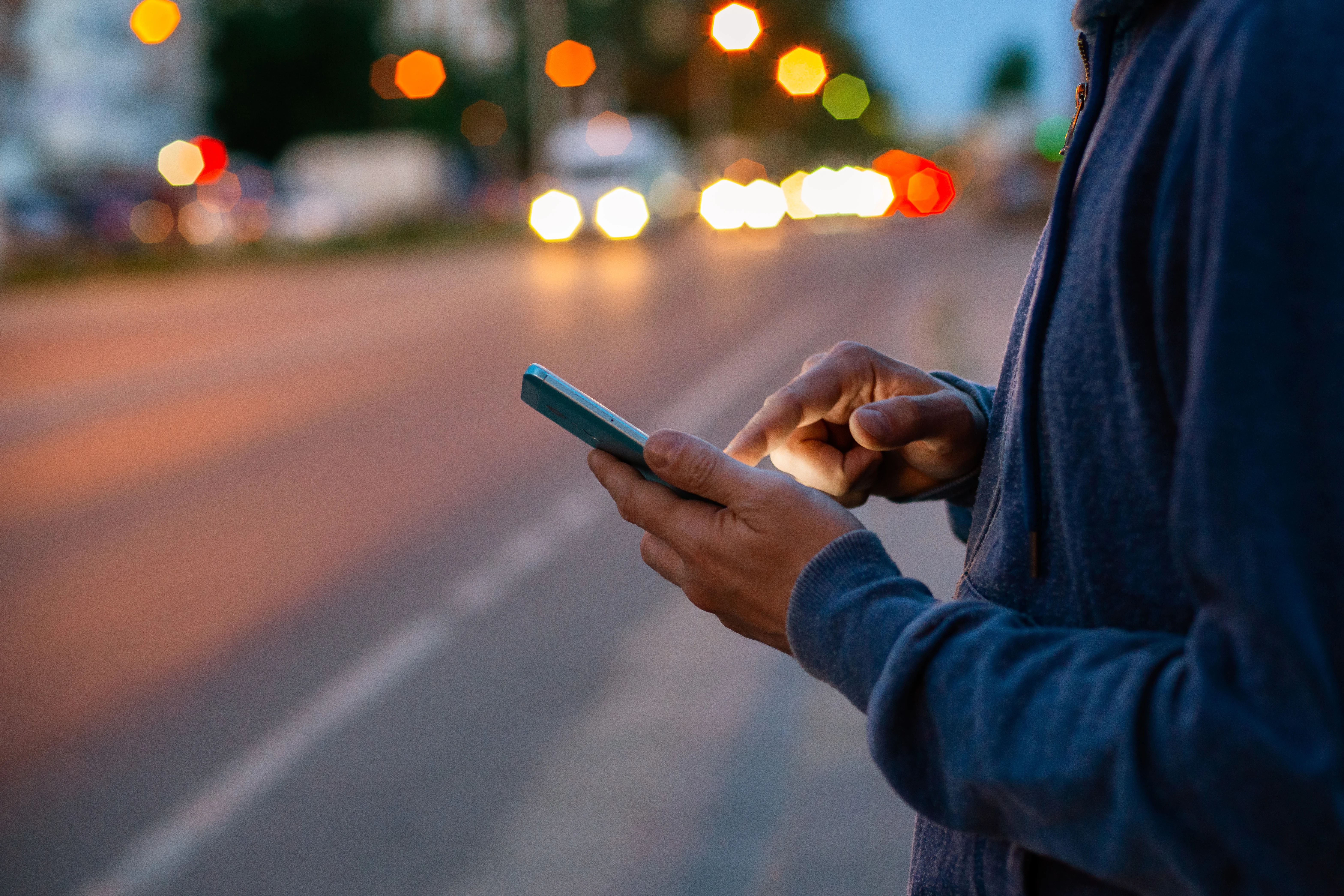 image of person's hands using a phone in low light