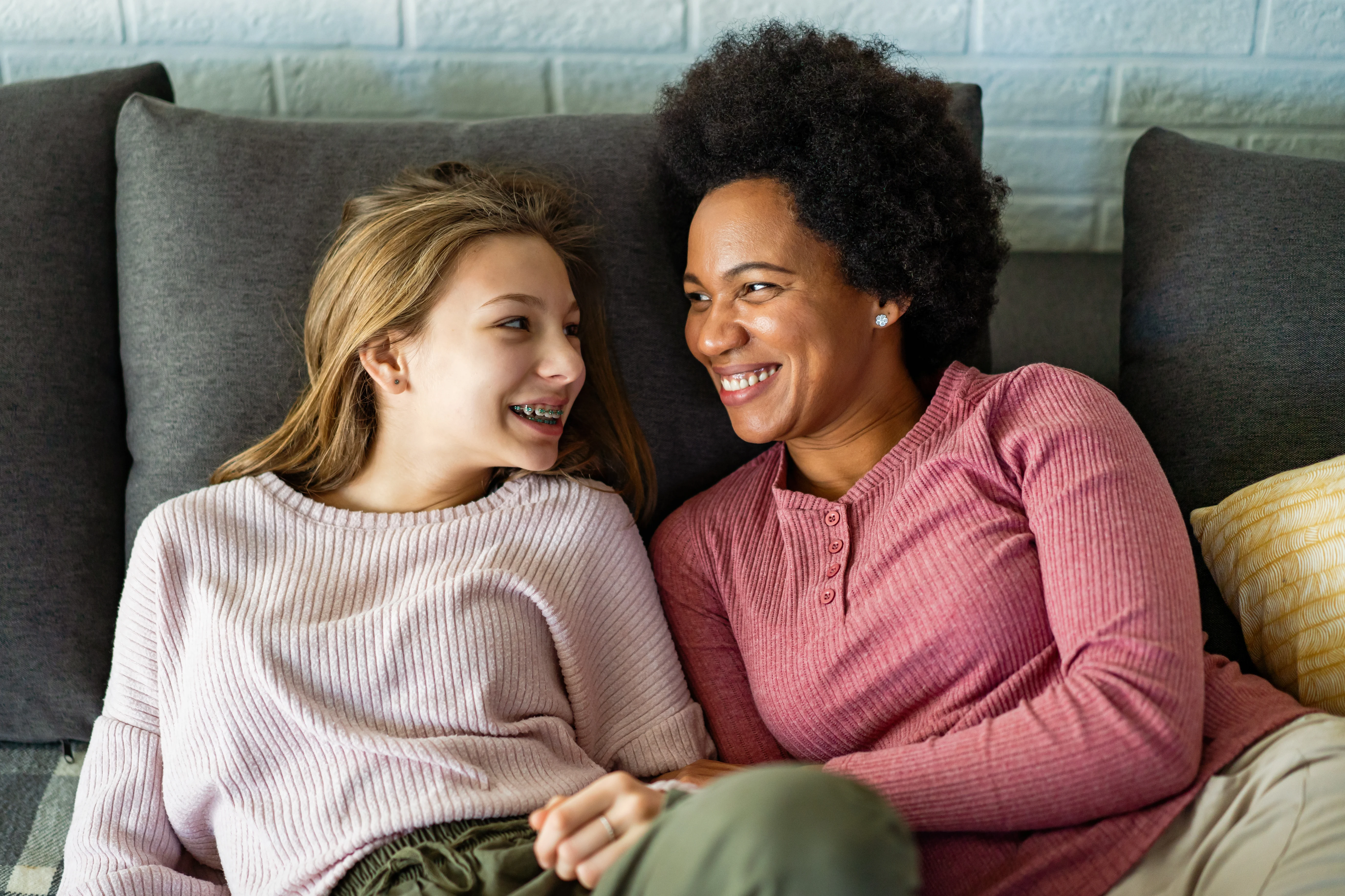 image of mother and daughter sitting on couch and smiling at each other