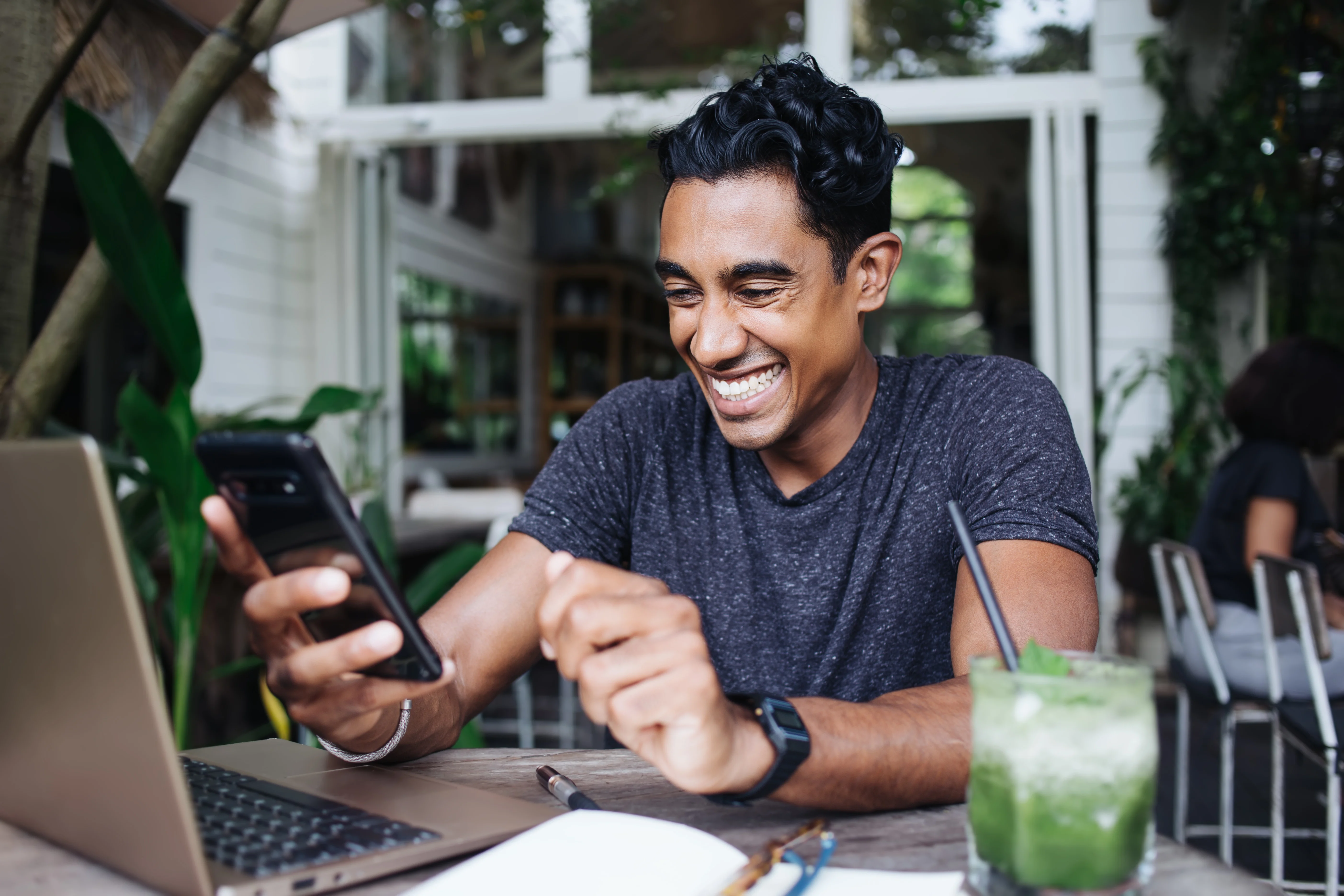 a man smiling looking at his phone in an outdoor cafe
