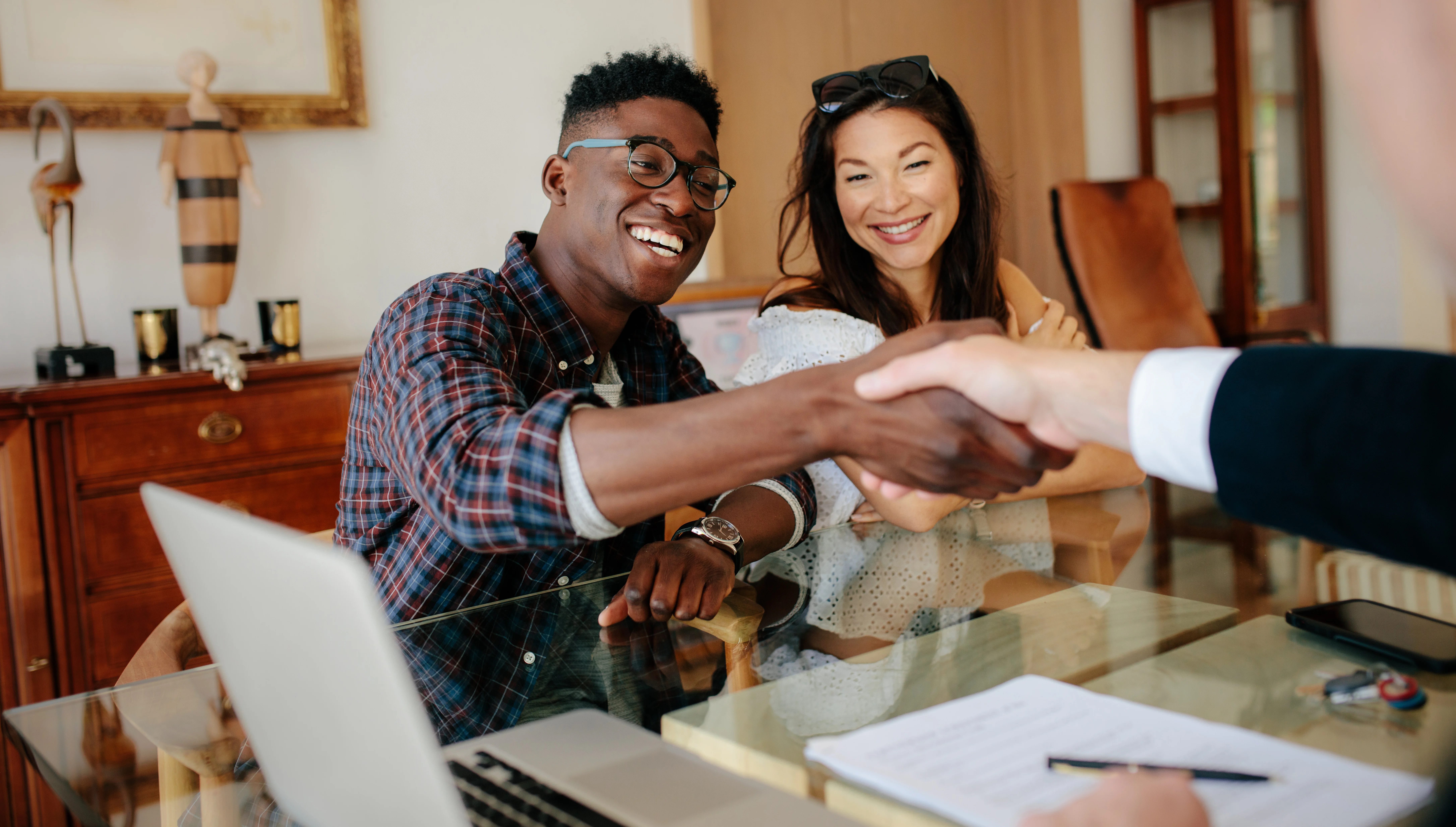 man and woman sitting at a desk - man shaking another person's hand across a desk