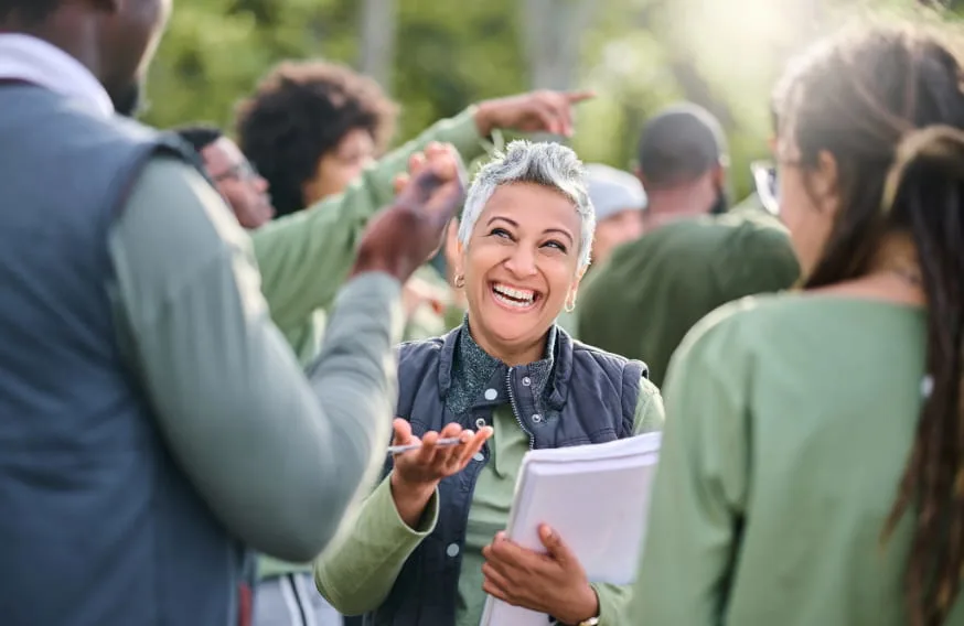 woman with short hair smiling while holding stack of papers