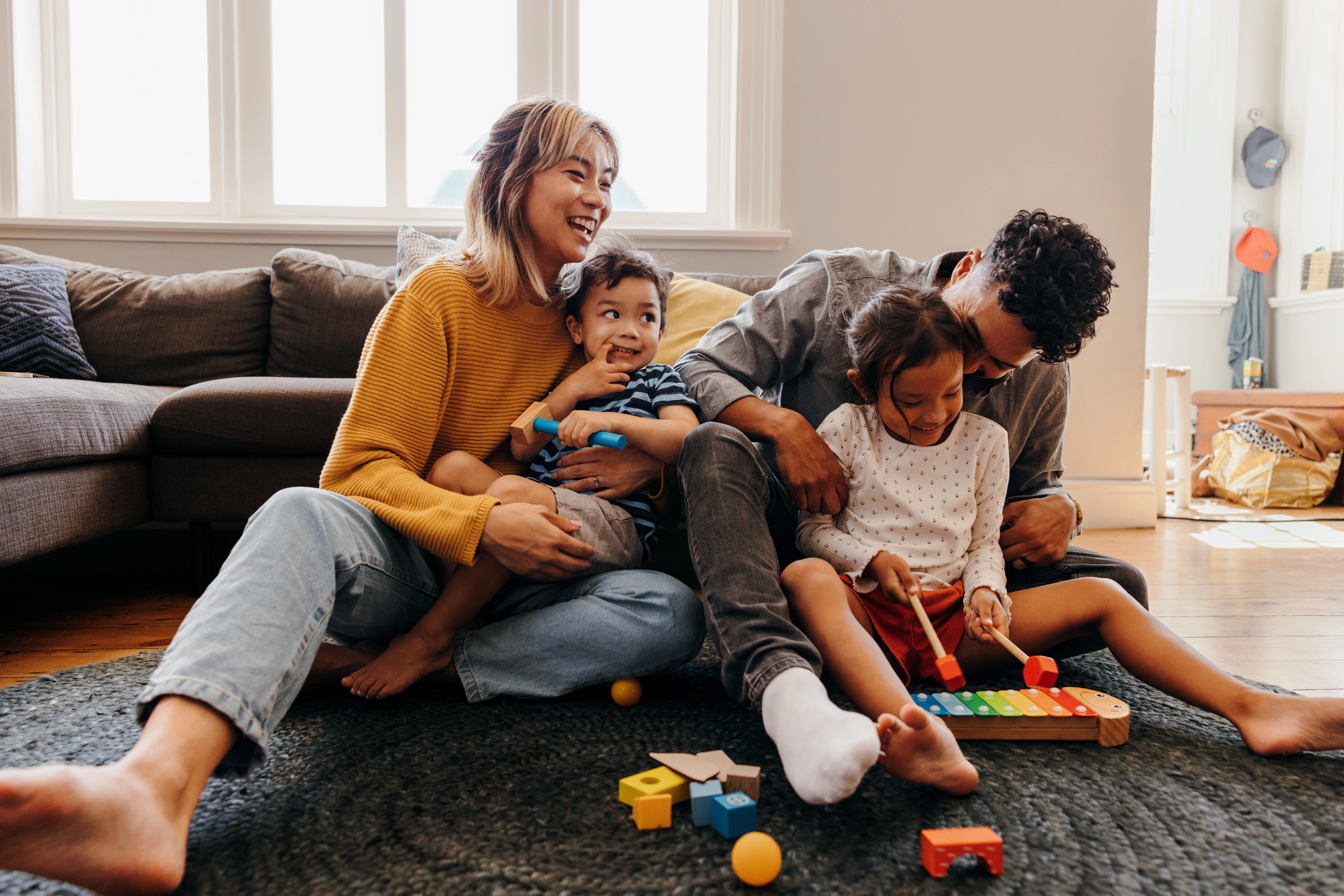 family of 4 smiling and having fun in living room