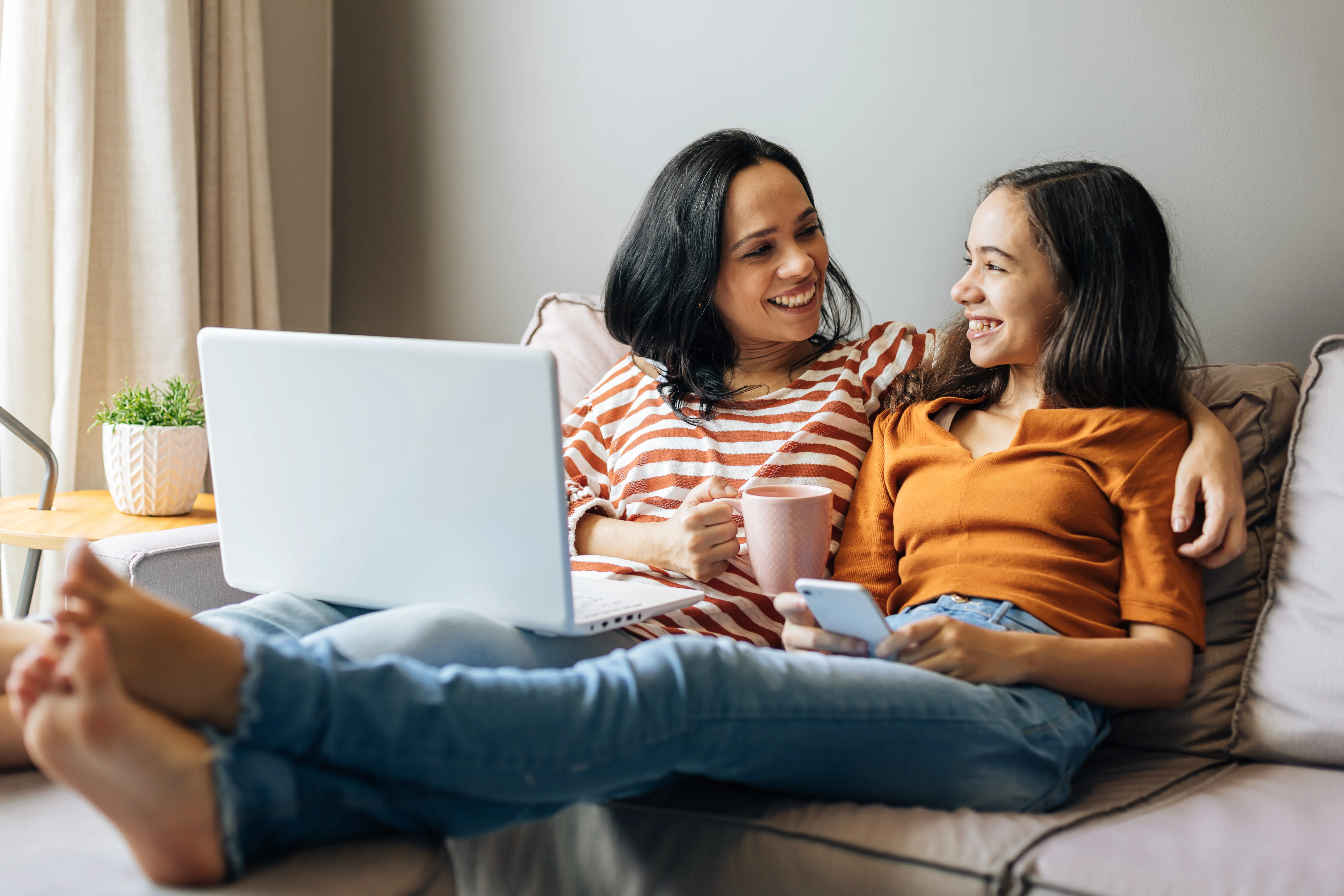 mother sitting with her arm around her daughter while online shopping