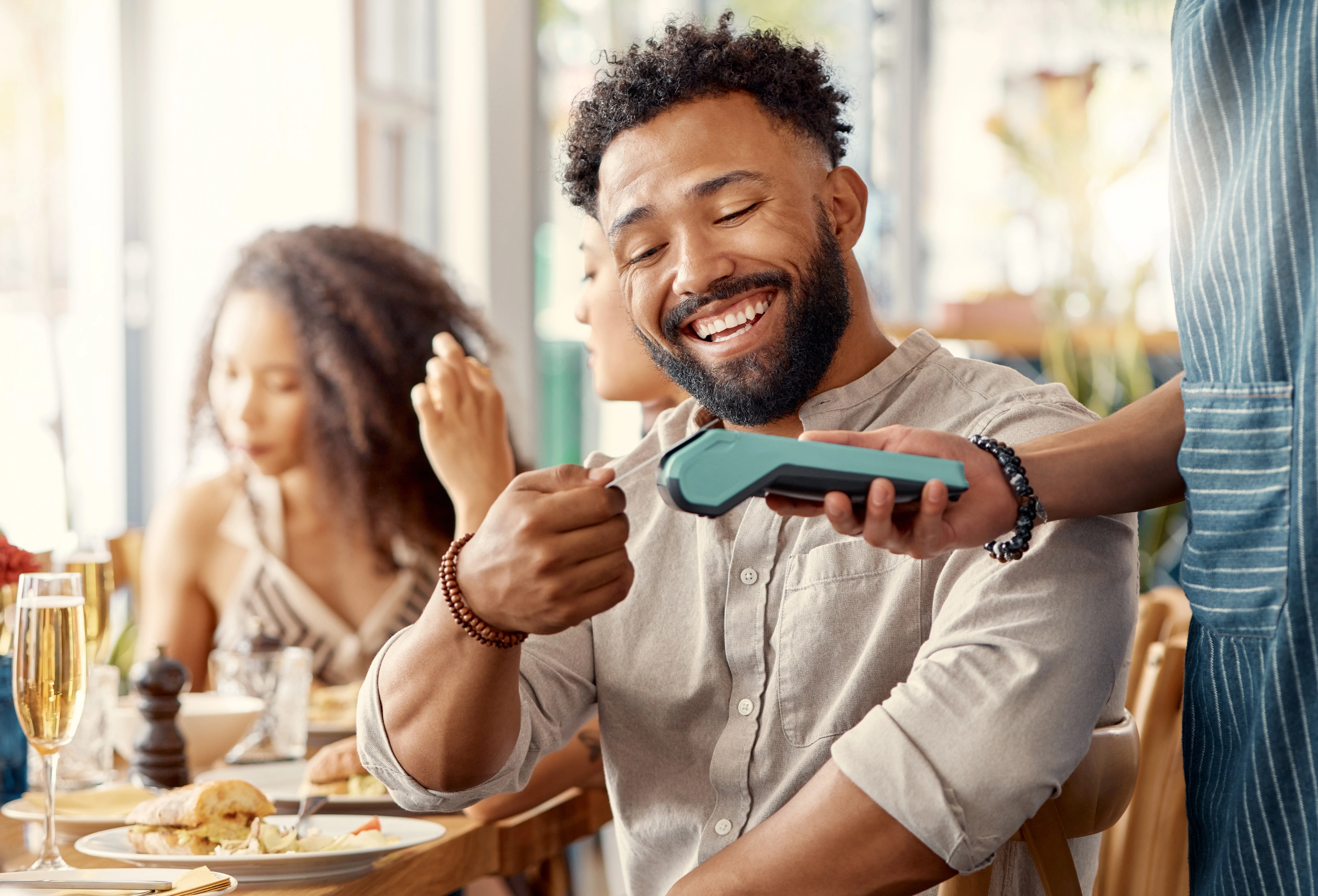 man smiling while paying with his credit card at a restaurant
