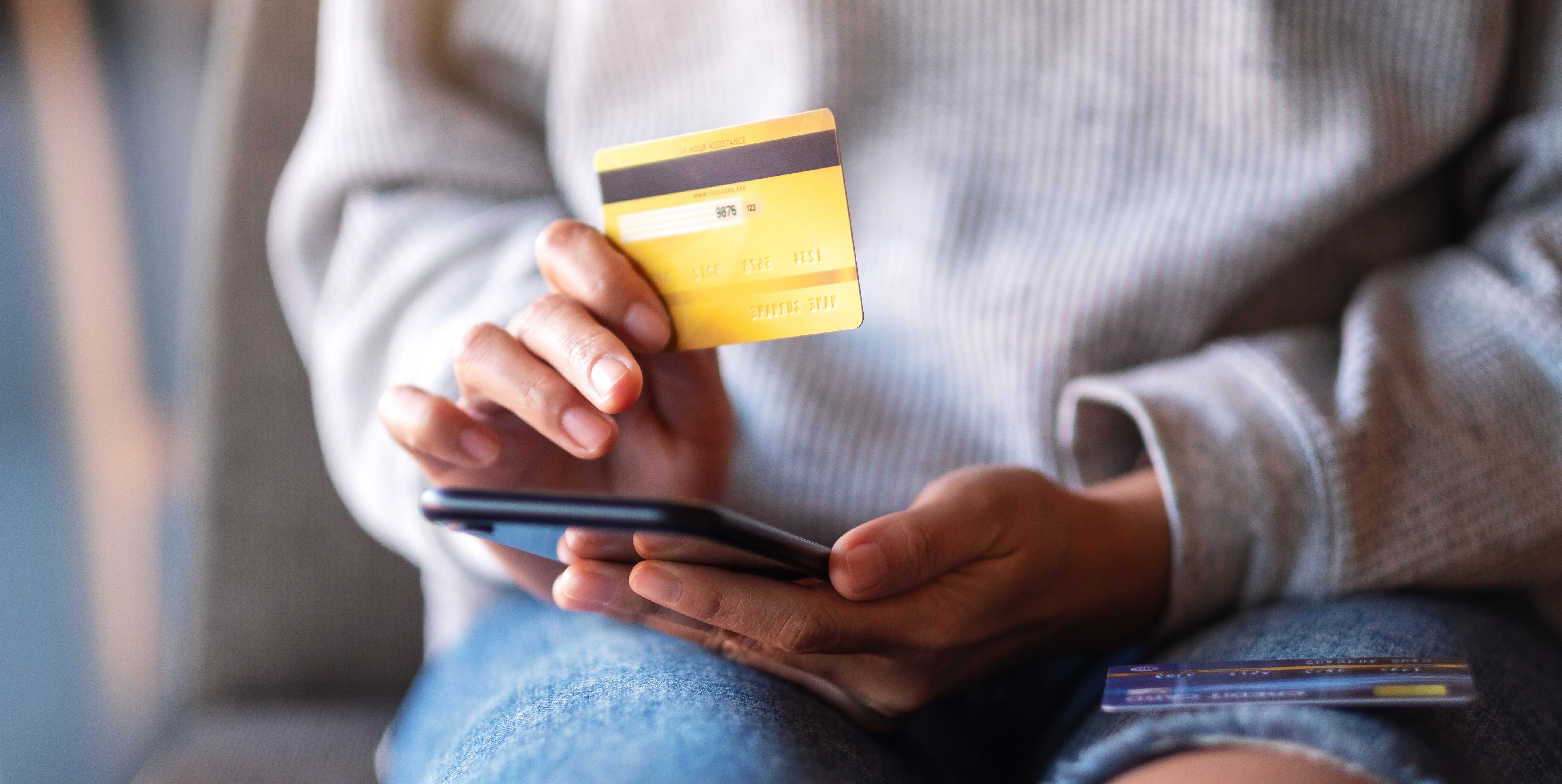 close up of person holding phone with a yellow credit card