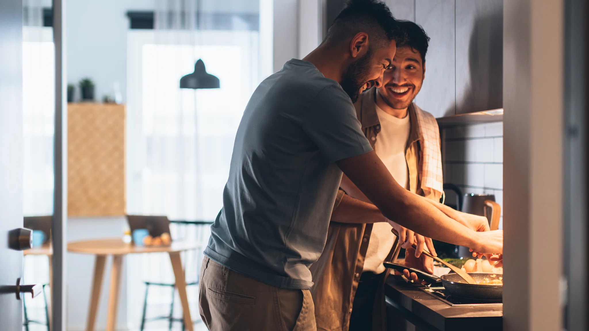 couple smiling and cooking in their home's kitchen together